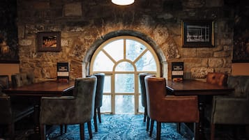 A restaurant with a stone wall, arched window, and a blue patterned carpet.