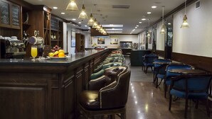 Un espace bar comprenant un comptoir, des tabourets de bar et un assortiment de fruits et de boissons.