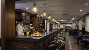 Un espace bar avec un barman, un présentoir de fruits et des fauteuils en cuir.
