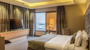 A modern hotel room with a large bed, a flat-screen TV, a glass coffee table, and a view of the sea. - Ewaa Express Hotel - Al hamra (Jeddah)