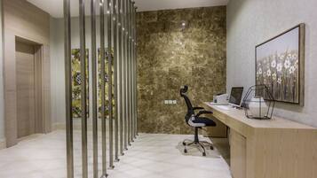 A modern office space with a marble wall, a desk with a computer, a chair, and a decorative painting.