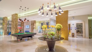 A modern lobby with a pool table, a decorative table with flowers, and a unique ceiling light fixture. - Ewaa Express Hotel - Al hamra (Jeddah)