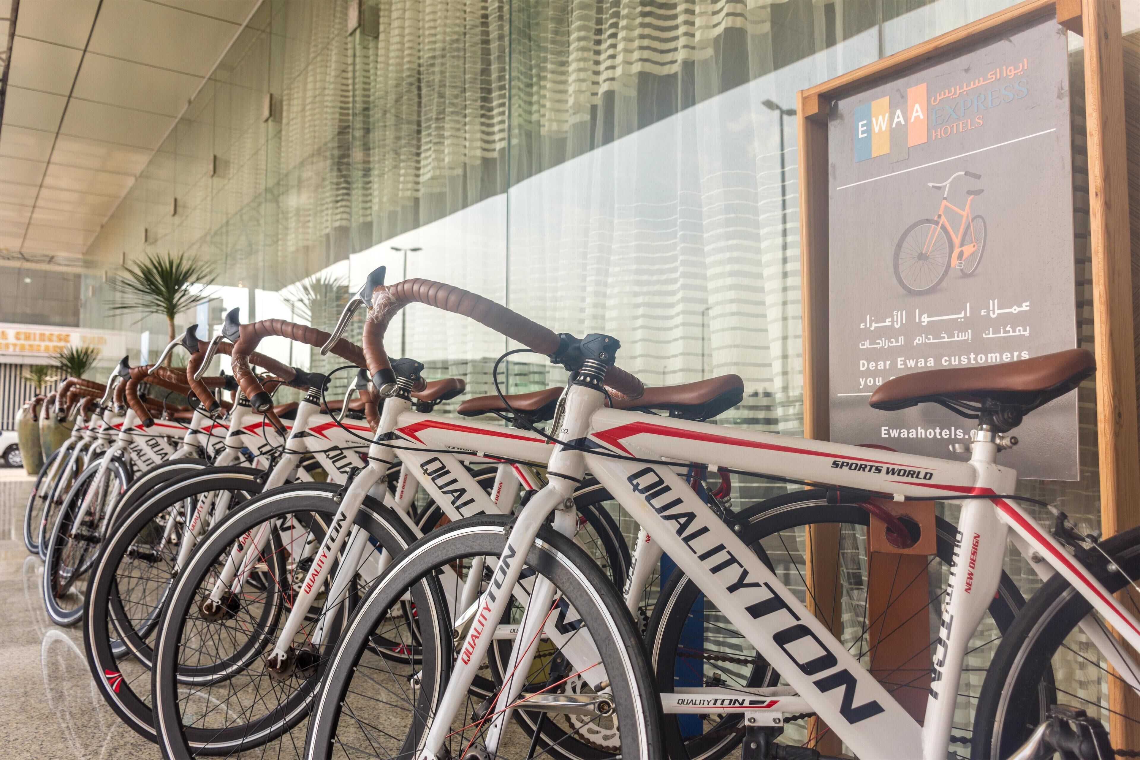 Une rangée de vélos portant la marque « QUALITYTON », devant un établissement affichant une enseigne pour EWAahotels.