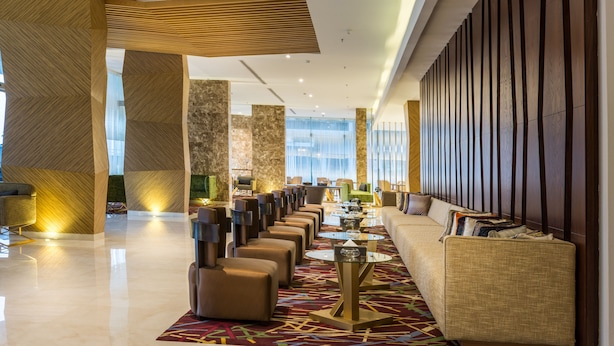 A modern lobby with a long reception desk, comfortable seating, and a patterned carpet. - Ewaa Express Hotel - Al hamra (Jeddah)