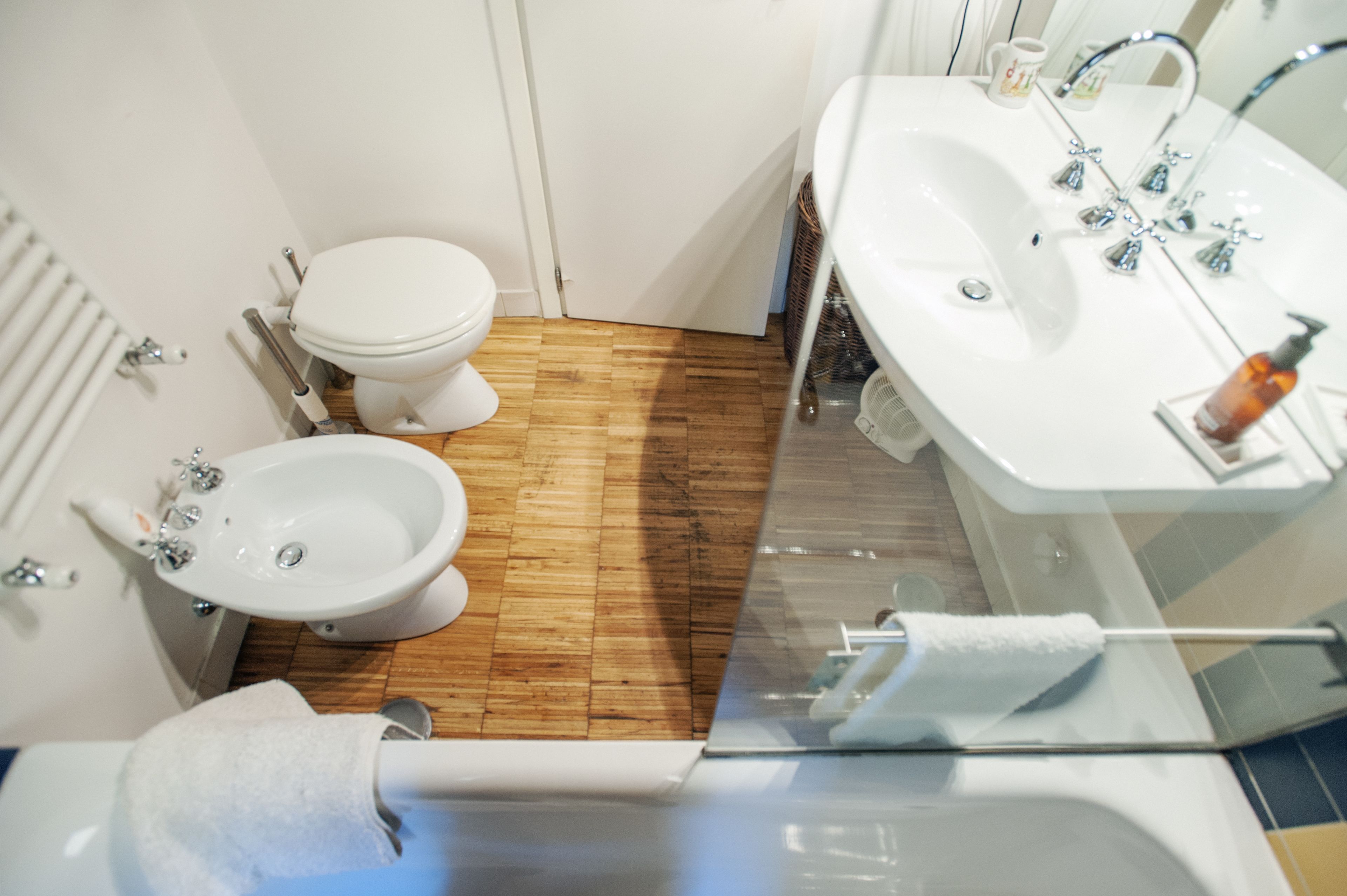 Ein Badezimmer mit Toilette, Bidet und einem großen Waschbecken mit mehreren Wasserhähnen.