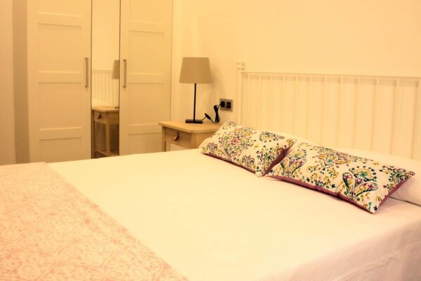 Une chambre à coucher avec un lit, deux oreillers, une table de chevet, une lampe et un radiateur.