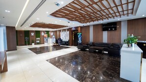 A modern hotel lobby with a reception desk, seating area, and a large screen displaying content. - Smana Hotel Al Raffa (Dubai)