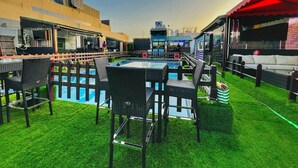 An outdoor pool area with a table and chairs, surrounded by a wooden fence. - Smana Hotel Al Raffa (Dubai)