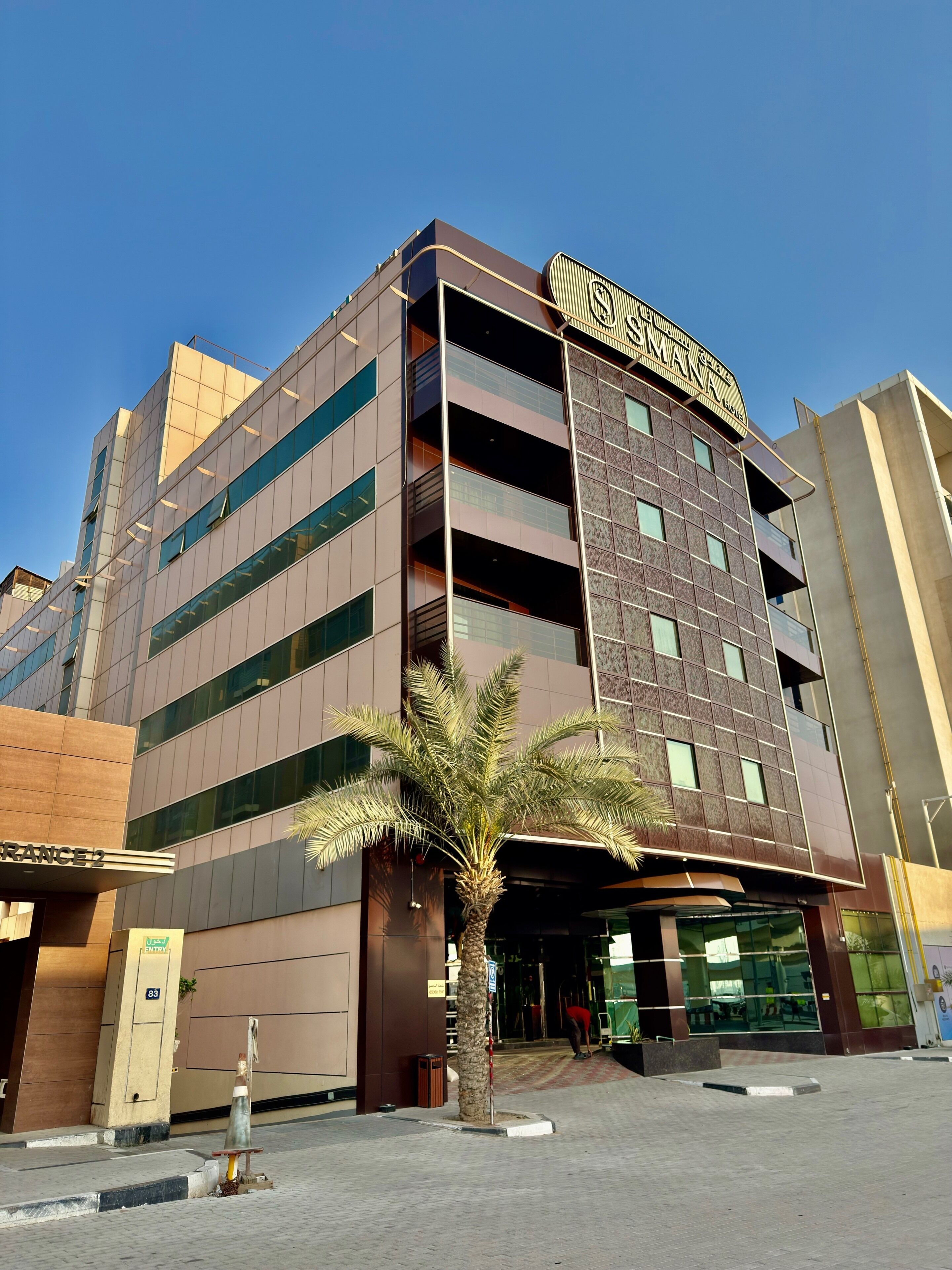 A modern hotel with a prominent sign, multiple floors, and a palm tree in the foreground.