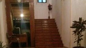 Una escala que porta a un pis superior, amb una planta en testos a la dreta i una cadira a l'esquerra.