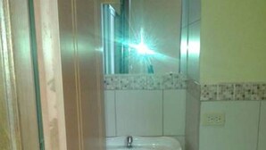 Un bany amb un lavabo blanc, un vàter i un mirall sobre el lavabo.