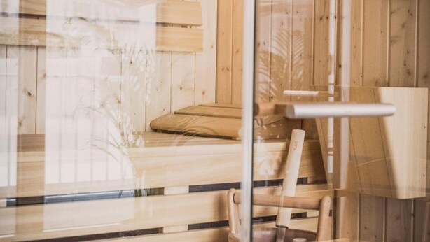 A wooden sauna with a glass door, a wooden bench, and a wooden bucket. - HENRI Hotel Düsseldorf (Düsseldorf)