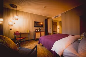Une chambre d’hôtel avec un lit, un bureau, une chaise et une armoire.