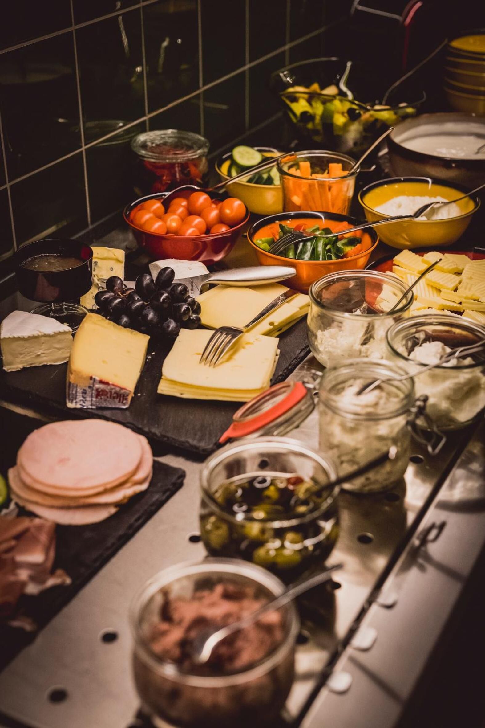Una mesa de buffet con diversos quesos, frutas y salsas.