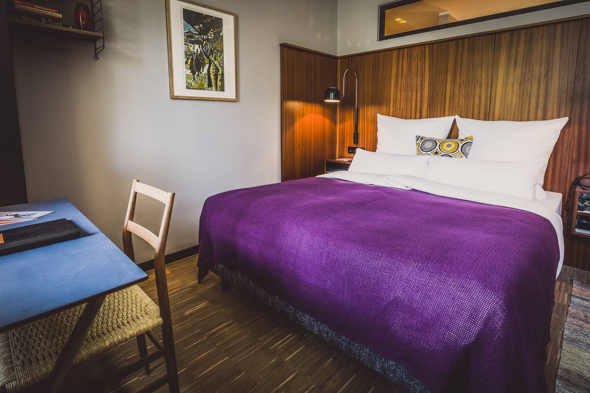Une chambre d’hôtel avec un lit, un bureau et une chaise.