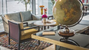 A modern interior with a sofa, round table, globe, and decorative flowers. - HENRI Hotel Düsseldorf (Düsseldorf)