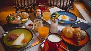 A breakfast setting with a table set for two, including plates with eggs, pastries, and beverages. - HENRI Hotel Düsseldorf (Düsseldorf)