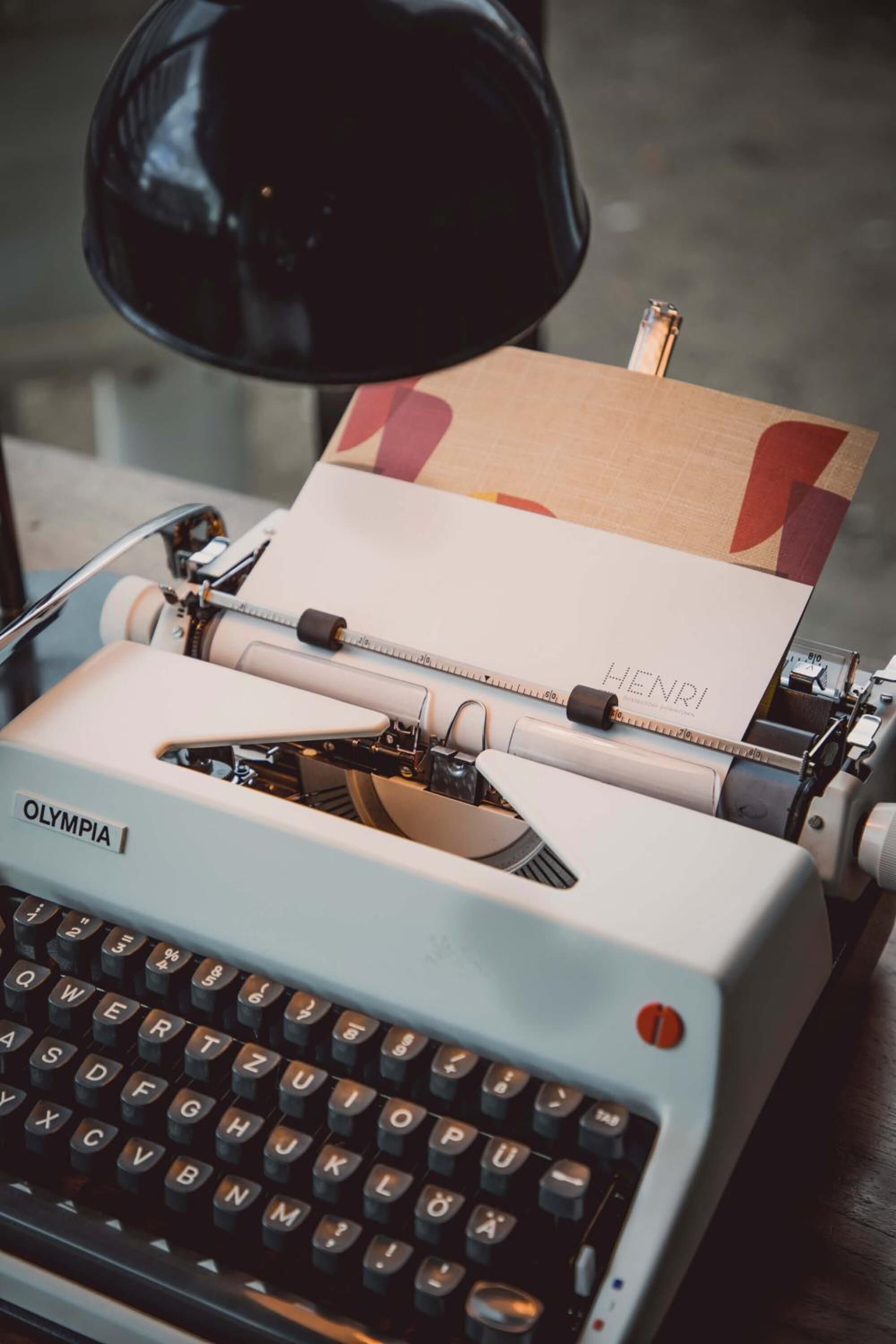 Uma máquina de escrever Olympia antiga com um papel etiquetado 'HENRI' em frente.