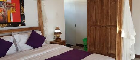 A bedroom with a bed, a nightstand, a lamp, a wardrobe, and a painting on the wall.