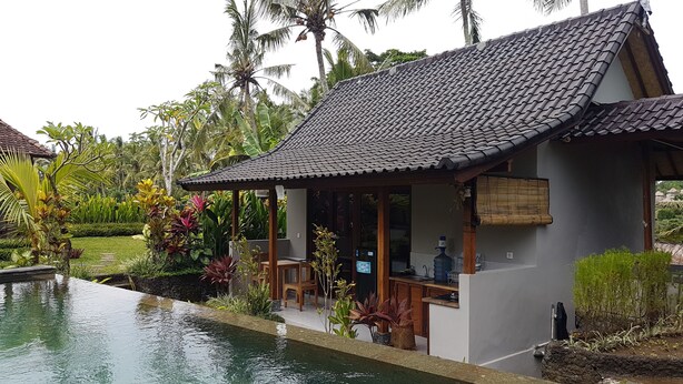 A house with a tiled roof, a pool, and lush tropical vegetation. - Buda Cottage Ubud (Ubud)