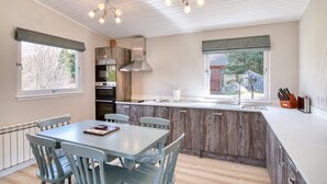Een moderne keuken met houten kastjes, een centraal eiland en een eethoek met stoelen.