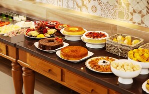 Una mesa de buffet con diversos platos, incluyendo pasteles, frutas y repostería.