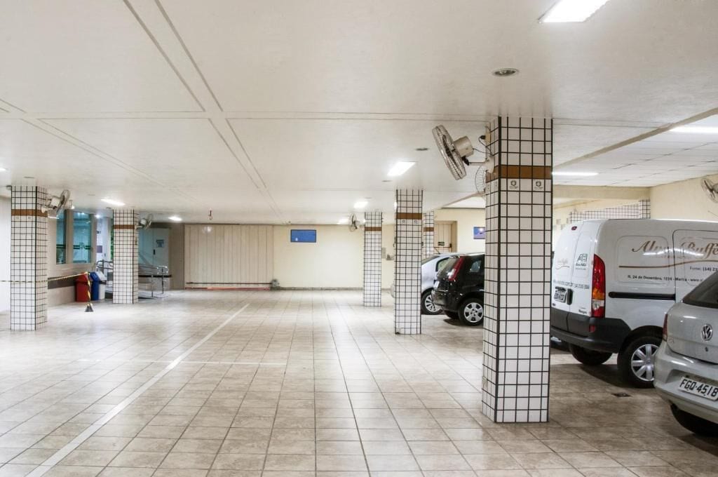 Un garaje para estacionar con pisos de baldosas, columnas con diseños de cuadrícula y ventiladores de techo.