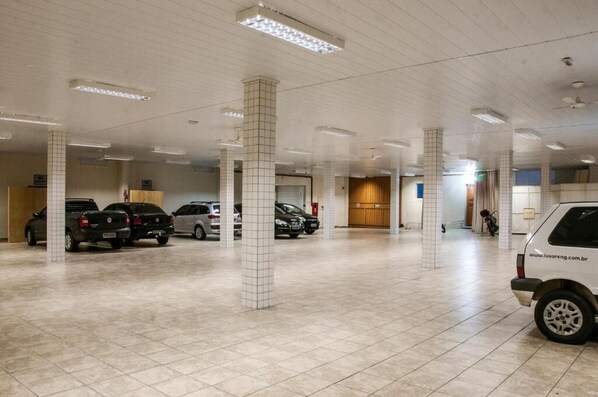 Amplio estacionamiento interior con múltiples columnas y varios vehículos estacionados.