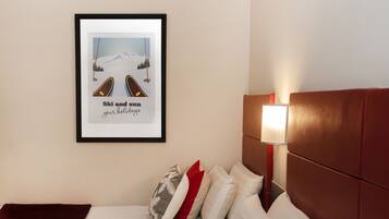 A hotel room with two beds, a framed picture on the wall, and a bedside lamp.