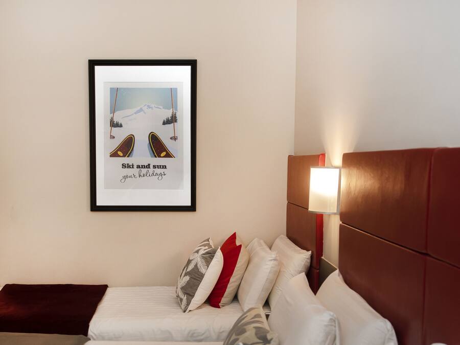 A hotel room with two beds, a framed picture on the wall, and a bedside lamp.