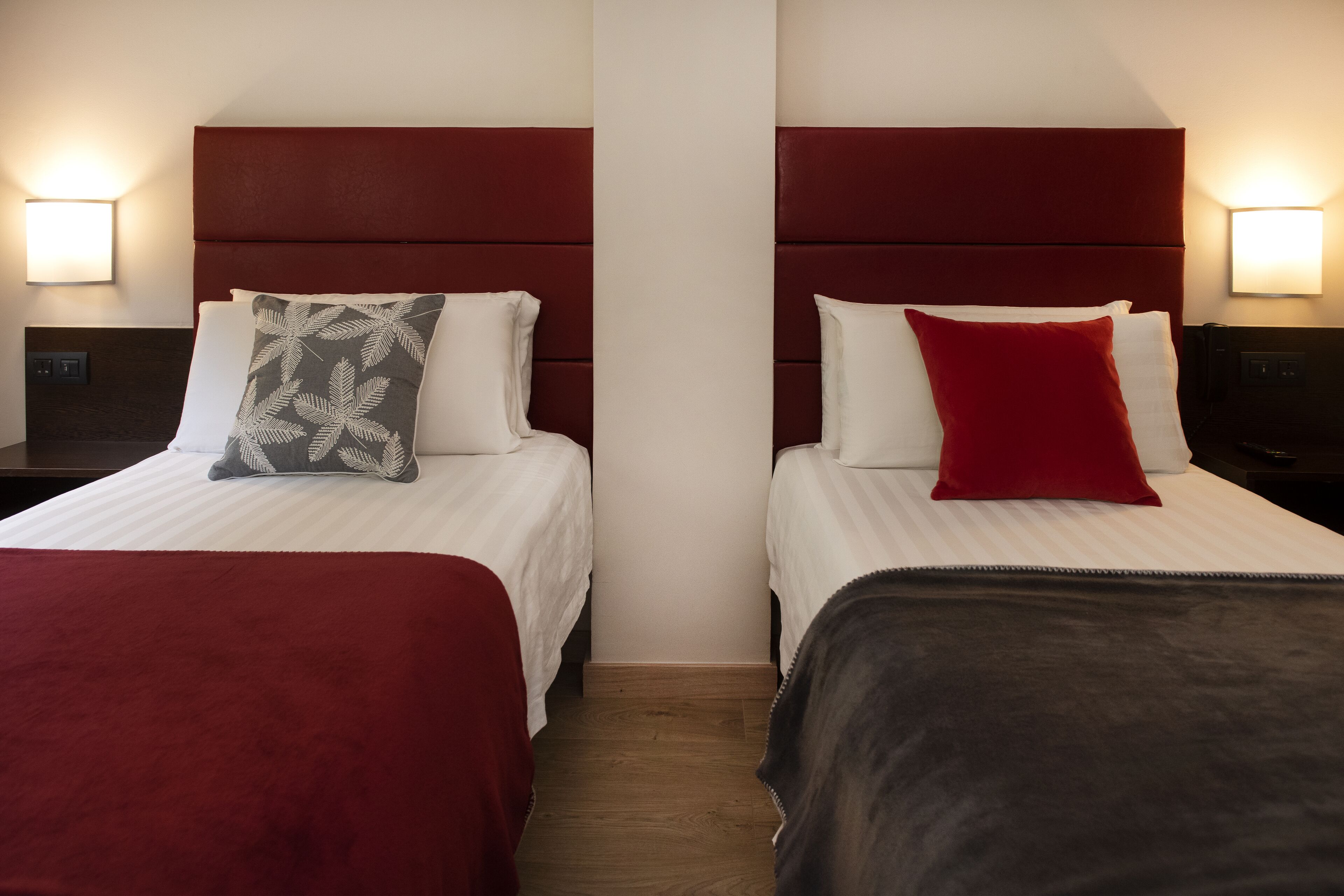 A hotel room with two beds, each with a distinct headboard and pillow.