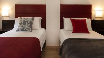 A hotel room with two beds, each with a distinct headboard and pillow.