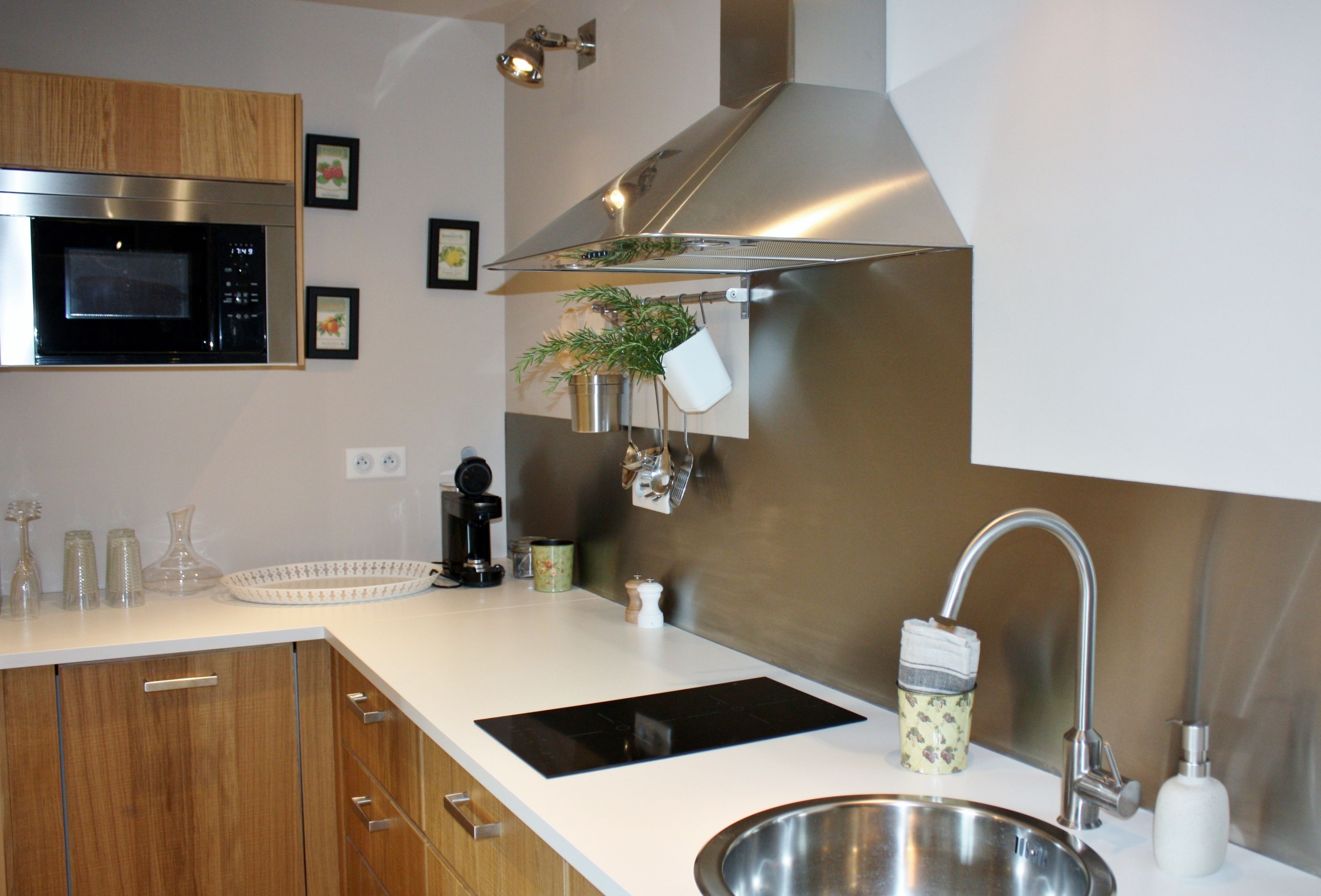 Een moderne keuken met een roestvrijstalen spoelbak, een magnetron en houten keukenkastjes.