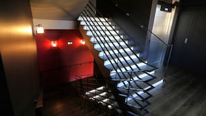 A modern staircase with glass railings and a red accent wall. - Apparthôtels de Val-Perrière (Arbois)
