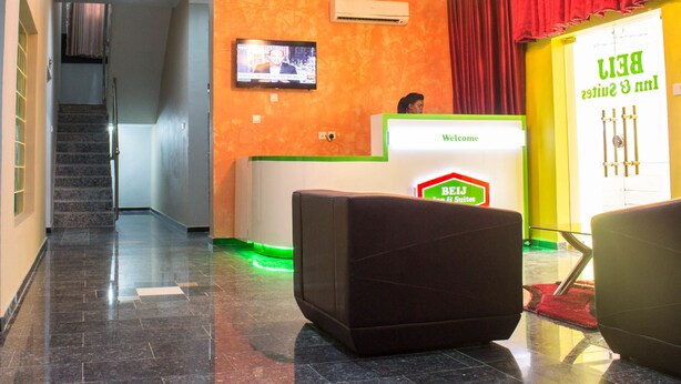 Un'area della reception di un hotel, con scrivania, televisione a muro e una scala che porta a un altro piano.