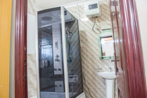 A bathroom with a glass-enclosed shower, a white sink, and a mirror above it. - Beij-Inn & Suite Limited (Lagos)