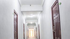 Un lungo e stretto corridoio con porte su entrambi i lati, che conduce a una stanza luminosa in fondo.