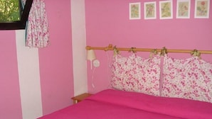 A pink room with a bed, a lamp, and a window with a curtain. - Camping Rio Verde (Costacciaro)