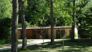 A small, single-story building with a tiled roof, surrounded by trees and grass. - Camping Rio Verde (Costacciaro)