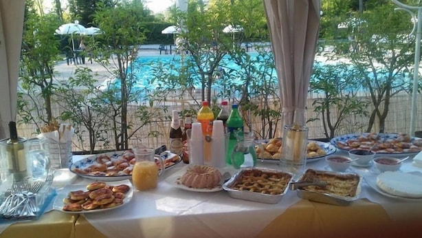 A buffet table with various dishes and drinks, overlooking a swimming pool. - Camping Rio Verde (Costacciaro)