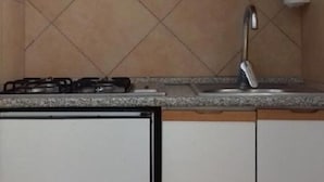 A kitchen with a gas stove, a sink, and cabinets. - Camping Rio Verde (Costacciaro)