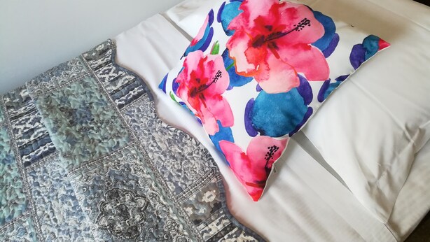 A bed with a floral pillow and a patterned throw blanket. - Venice Agostino Guesthouse (Mestre)