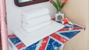 A bathroom with a mirror, a sink with stacked white towels, a small table with a Union Jack tablecloth, and a vase with tulips. - Venice Agostino Guesthouse (Mestre)