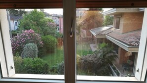 A view through a skylight window of a residential area with a garden, a brick house, and a patio with a table and chairs. - Venice Agostino Guesthouse (Mestre)