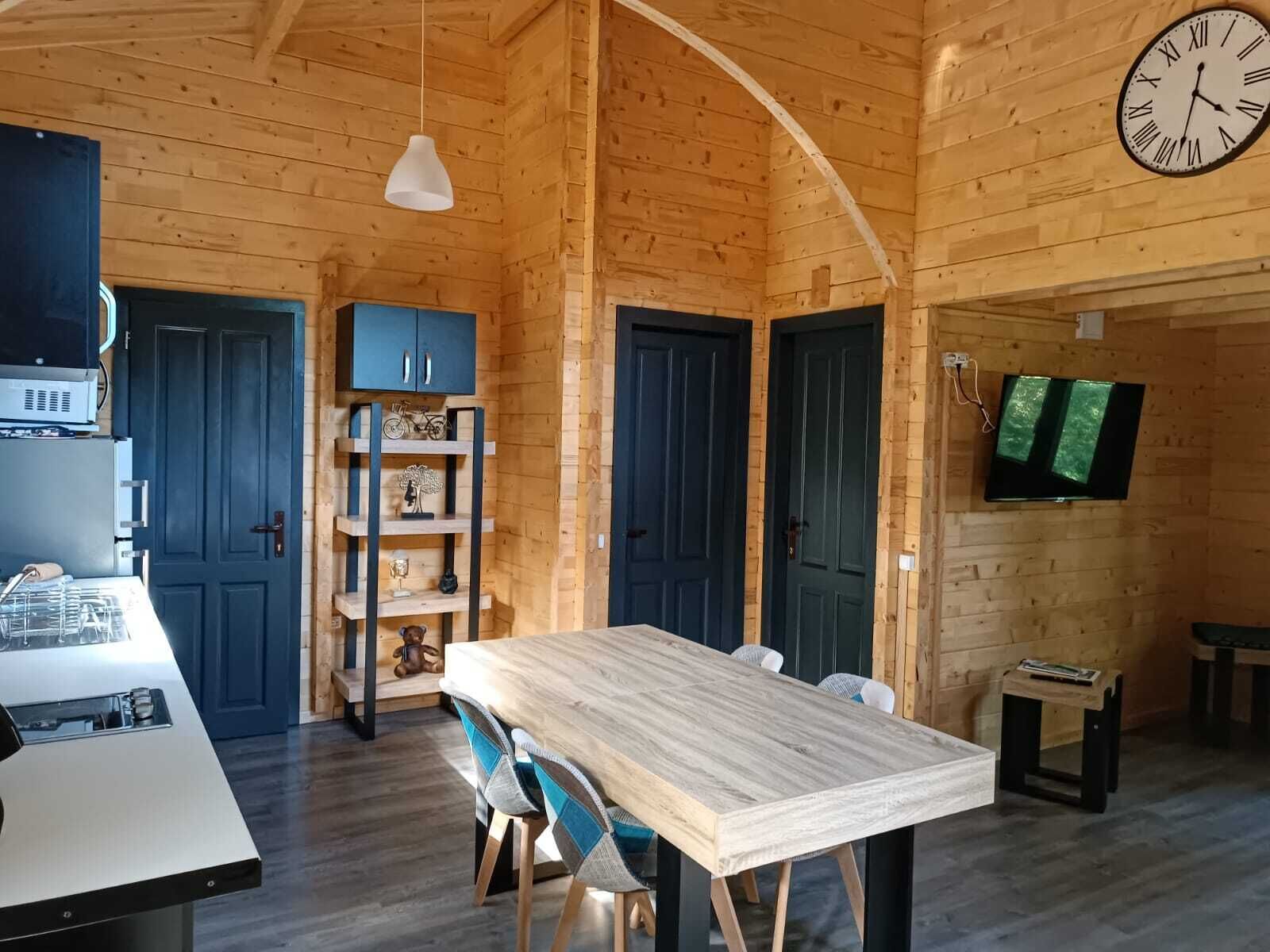 Een houten interieur met een eettafel, stoelen, een televisie en een klok.