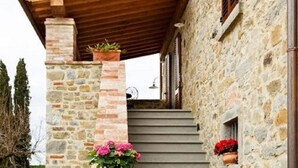 A stone staircase leading to a wooden-roofed porch with potted flowers. - Fattoria del Nonno Berto (Cortona)