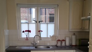 A compact kitchen with a washing machine, a sink, and a window with a view of a brick building. - 1 Sterling Court City Center (Canterbury)