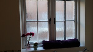 A bathroom with a frosted glass window, a pink vase with flowers, and a purple towel on the windowsill. - 1 Sterling Court City Center (Canterbury)
