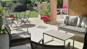 Un patio al aire libre con una mesa, sillas, un sofá y plantas en macetas.