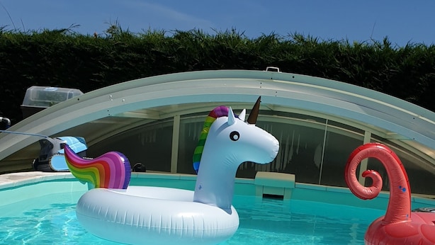 Una piscina con dos flotadores hinchables de unicornio y un flotador de cisne.